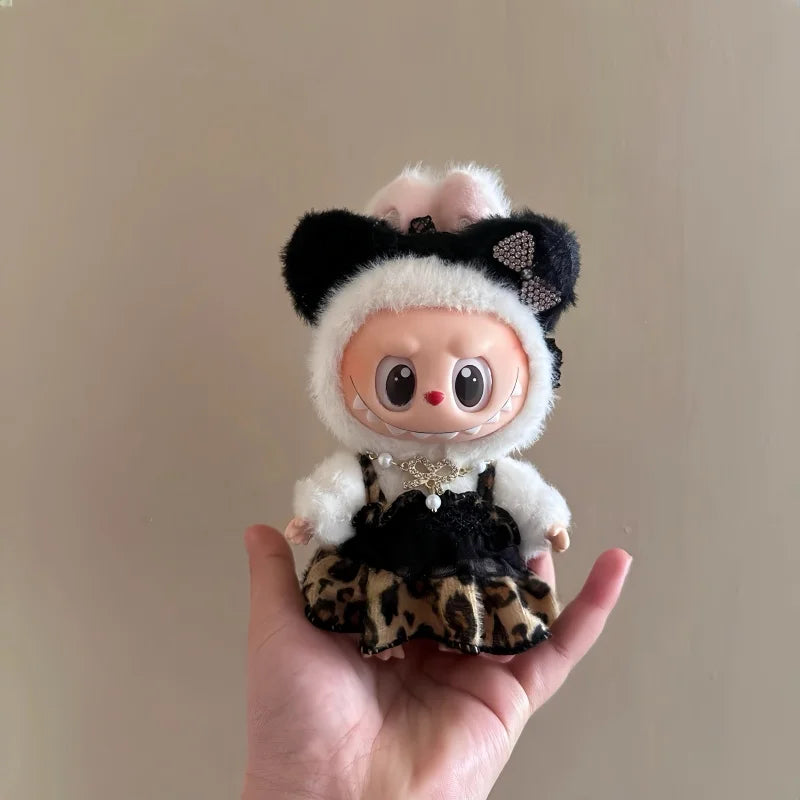 A plush doll dressed in a leopard print sling dress with white fur trim and black accents.