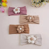 A collection of four floral elastic baby headbands in shades of pink, beige, and gray arranged on a light background.