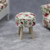 A small, round upholstered stool with wooden legs covered in a floral fabric for a dollhouse.