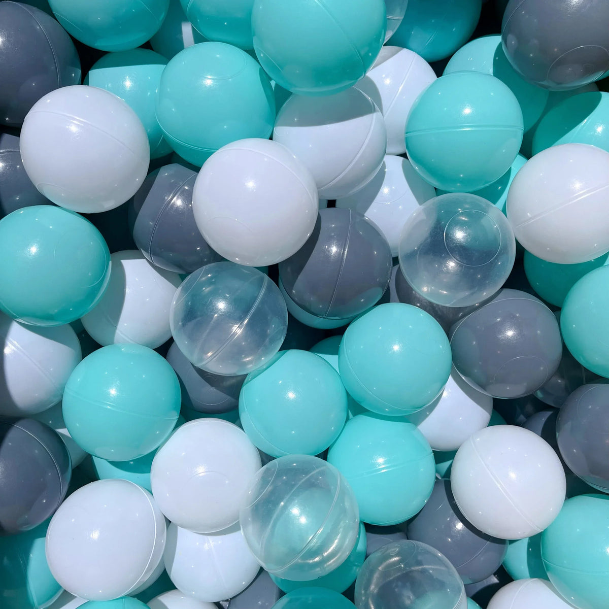 A close-up view of a large collection of colorful plastic play balls in various shades of blue, white, and gray.