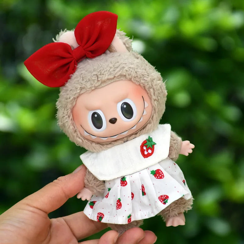 A plush doll wearing a strawberry party outfit with a red bow and white dress.