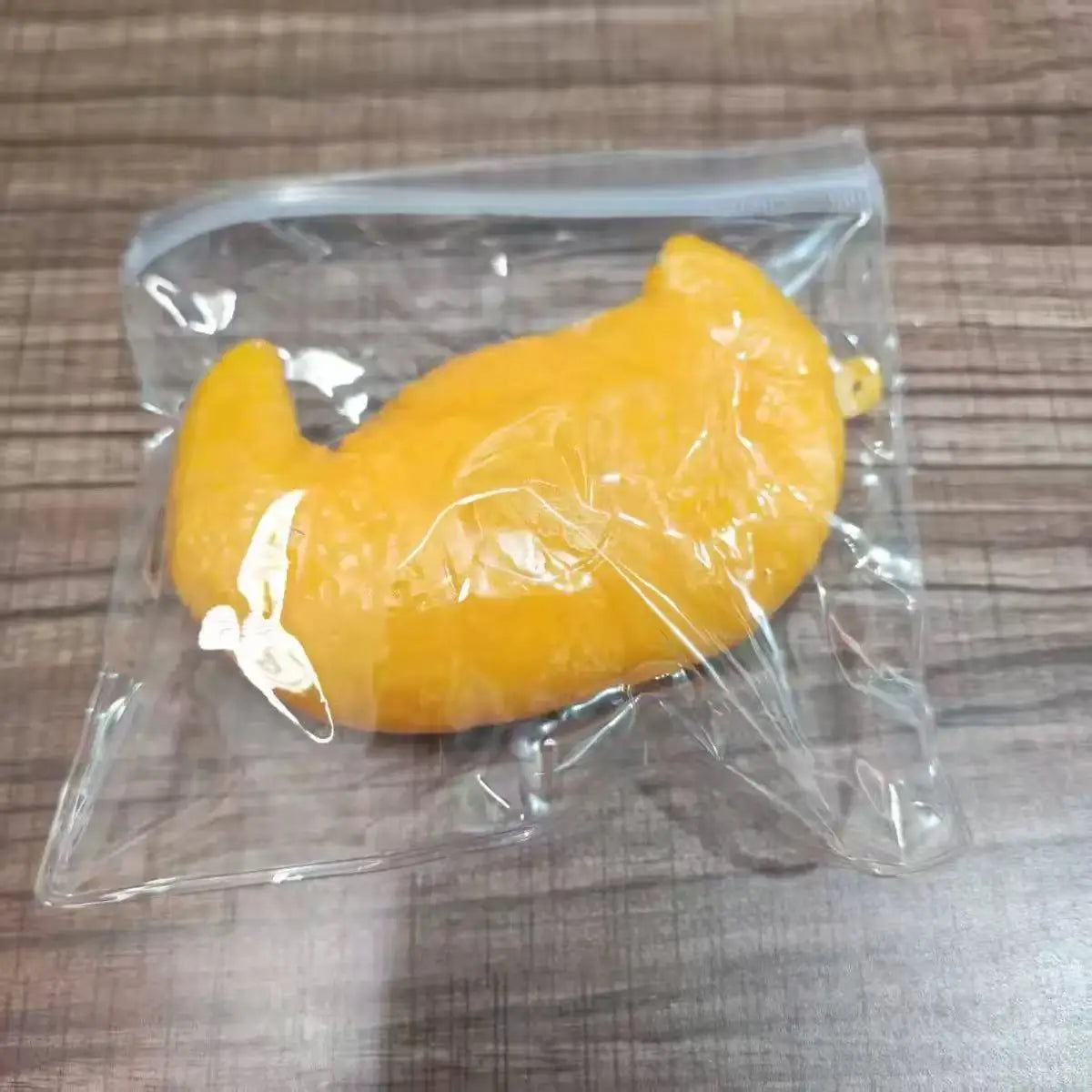 A yellow, squishy dog noodle stress relief toy is sealed in a clear plastic bag.