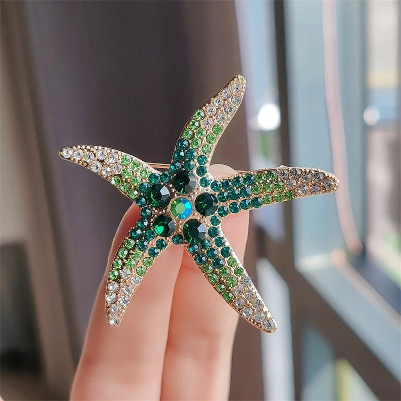A sparkling green and gold rhinestone turtle brooch pin displayed on a hand.