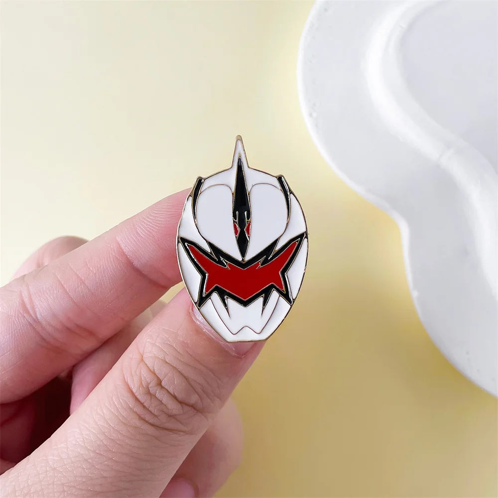 A hand holds a silver enamel pin featuring a red and black dinosaur ranger helmet design against a light background.