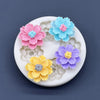 A silicone mold featuring various colored daisy flowers in pink, blue, purple, and yellow on a white background.
