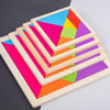 A wooden tangram puzzle set showing seven colored triangular pieces arranged in a pyramid formation.