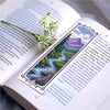 A DIY cross-stitch bookmark craft kit featuring a floral design and purple and blue patterned paper inside an open book.