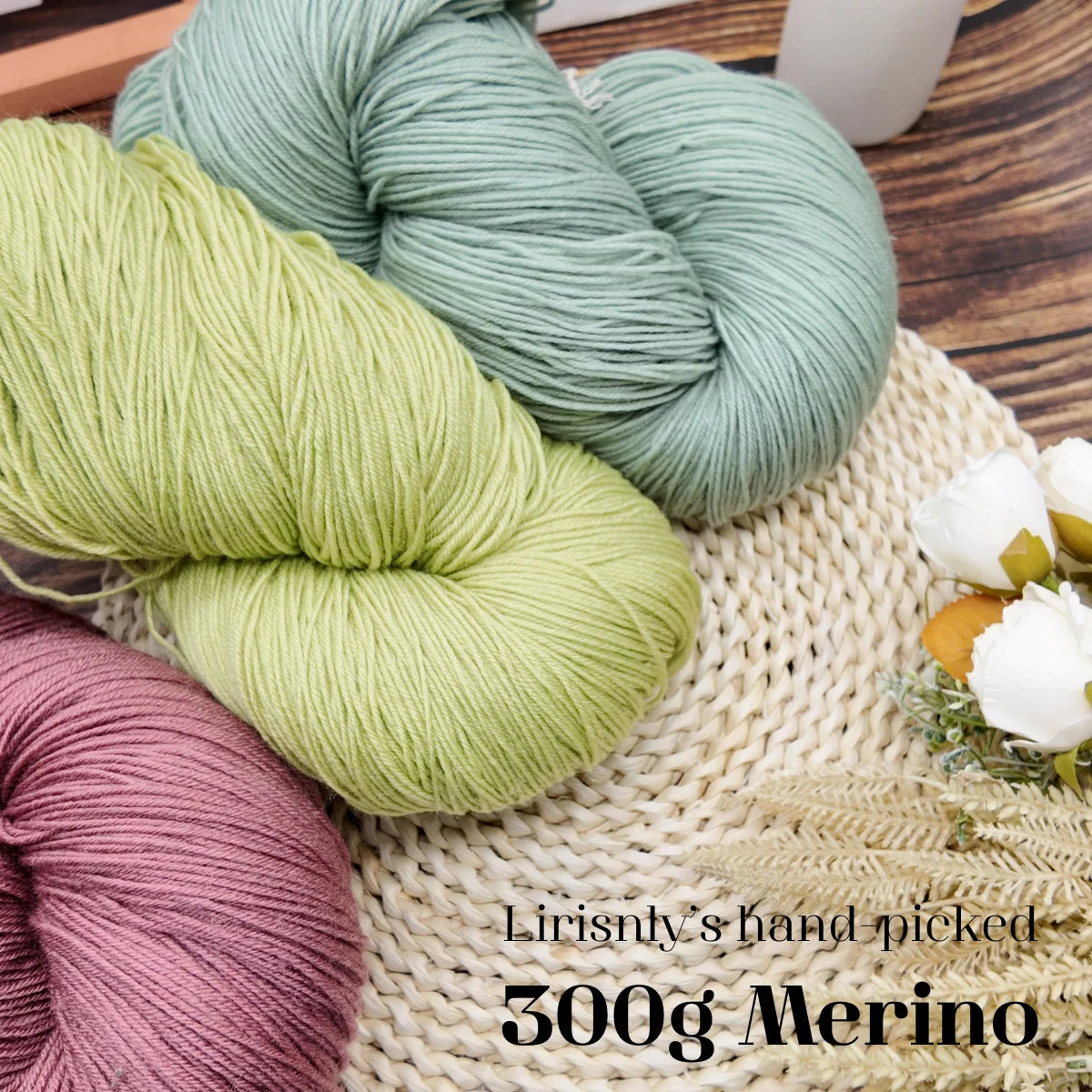 A pile of light green and pink merino wool yarn skeins resting on a woven fabric background.