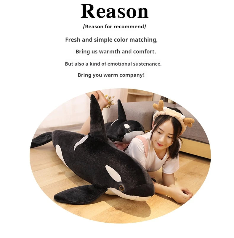 A person is cuddling a black and white lifelike orca whale plush toy on a couch.
