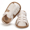 A pair of beige leather baby sandals with white woven straps and a soft anti-slip sole.