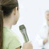 A young girl holds a realistic toy microphone prop while performing.