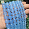 A hand holds a strand of natural light blue chalcedony beads for jewelry making