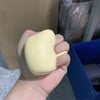 Une main tient un pain décoratif en pâte souple et jaune jouet.