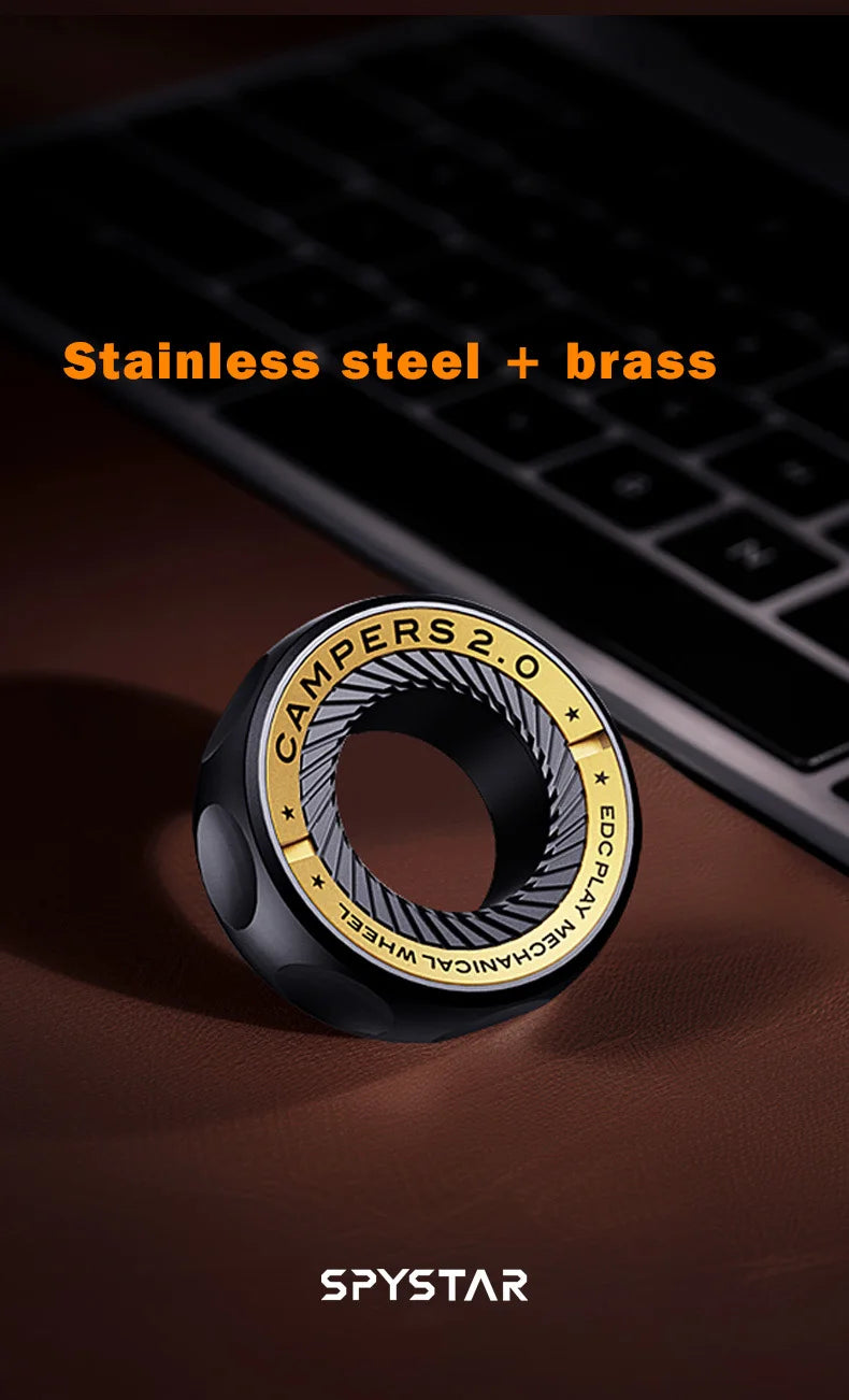 A black magnetic fidget ring labeled Campers 2.0 made of stainless steel and brass resting on a dark surface.