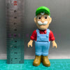 A playful cartoon PVC figurine of a man with a white mustache wearing a red shirt and blue overalls.