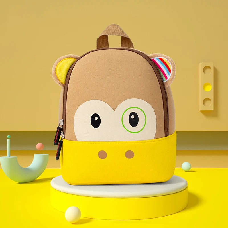 A yellow and brown 3D animal kids backpack with large eyes and ears sitting on a yellow surface.