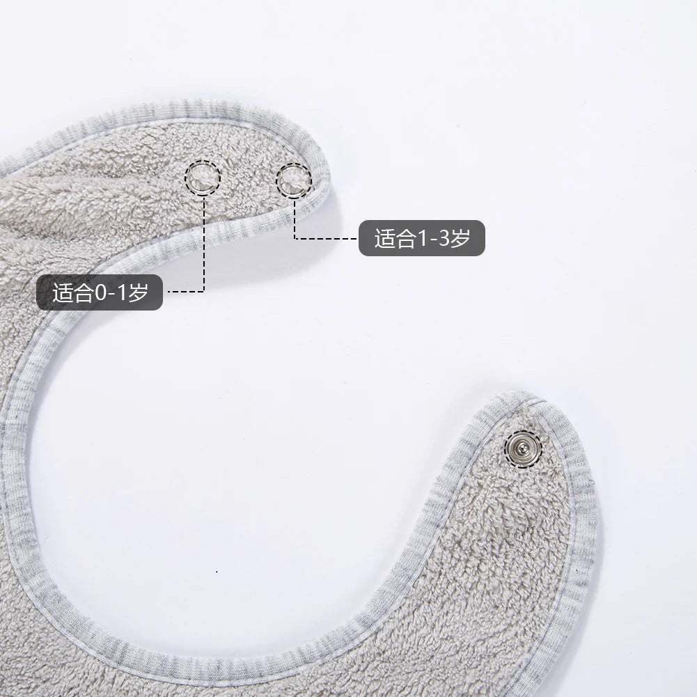 A close-up view of a gray soft cotton baby bib with an adjustable snap closure and various size options indicated.
