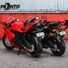 A red 1:18 scale die-cast motorcycle model is displayed against a corrugated metal background.