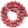 A circular arrangement of reddish-pink natural sea sediment jasper and turquoise beads for jewelry making