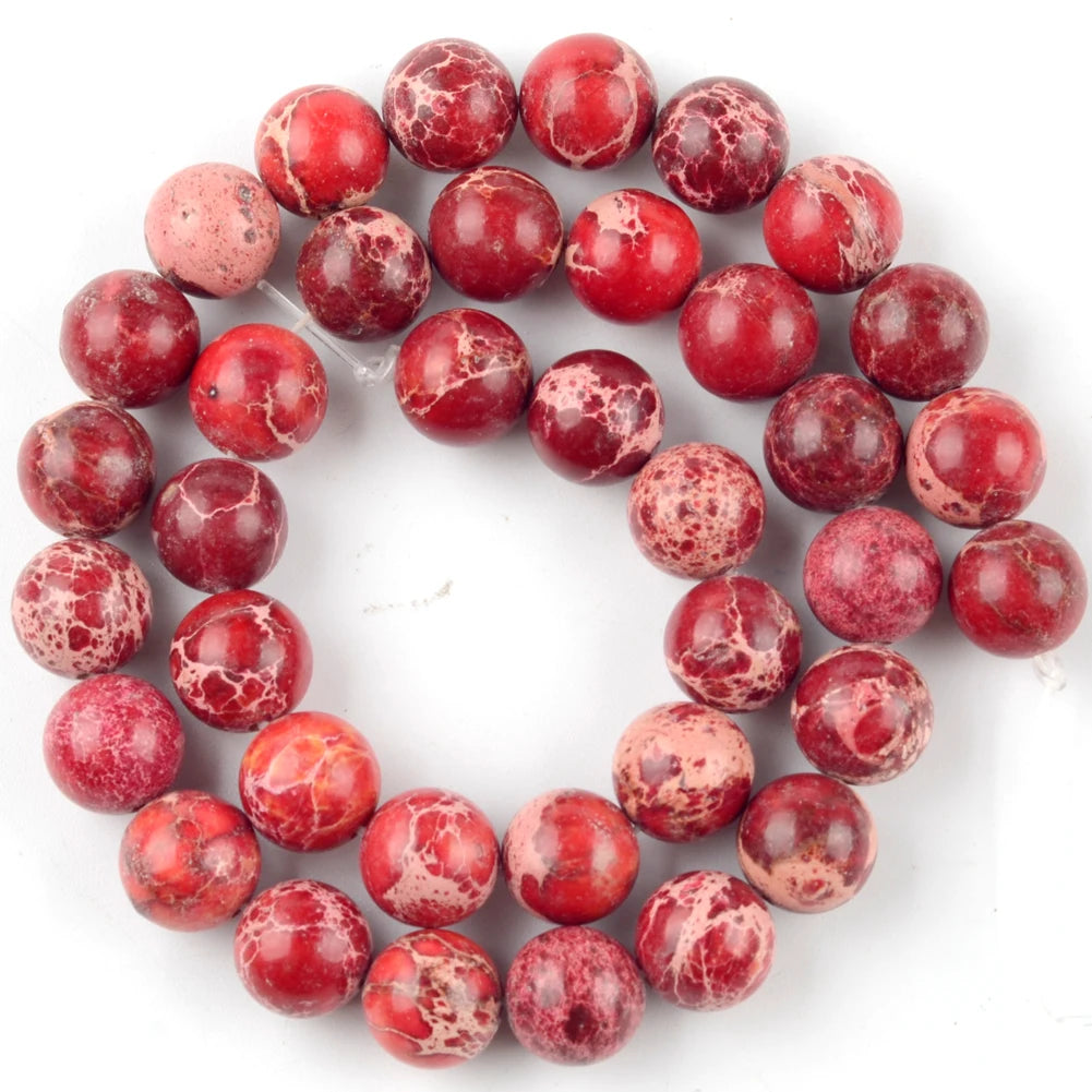 A circular arrangement of reddish-pink natural sea sediment jasper and turquoise beads for jewelry making