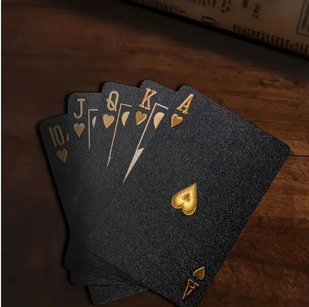 A stack of dark gray frosted poker playing cards showing the Ace through Jack, resting on a wooden surface.