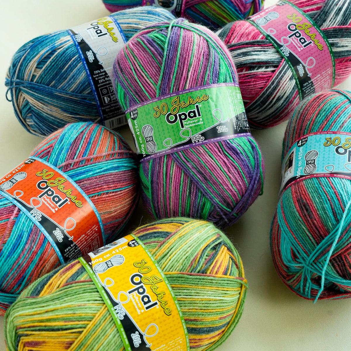 A collection of brightly colored Opal 4-ply sock yarn balls in various shades of pink, green, blue, and multi-colored blends.