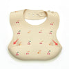 A beige soft silicone waterproof baby bib with an adjustable neck and small fruit illustrations.