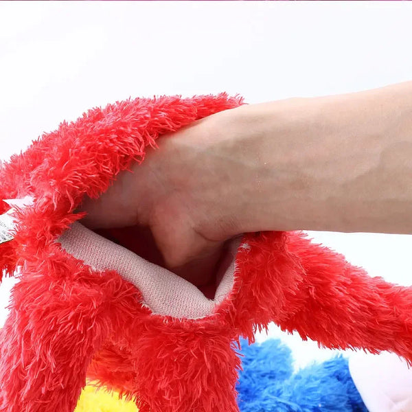 A hand is holding a large red fuzzy plush toy, likely a Sesame Street hand puppet.
