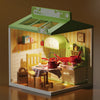 A miniature DIY dollhouse kit featuring a green and yellow room theme with furniture like a bakery and kitchen.