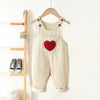 Cream corduroy overalls for a toddler featuring a red heart embroidery