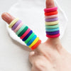 A hand displays a stack of colorful nylon hair ties in various shades of pink, purple, green, and yellow.