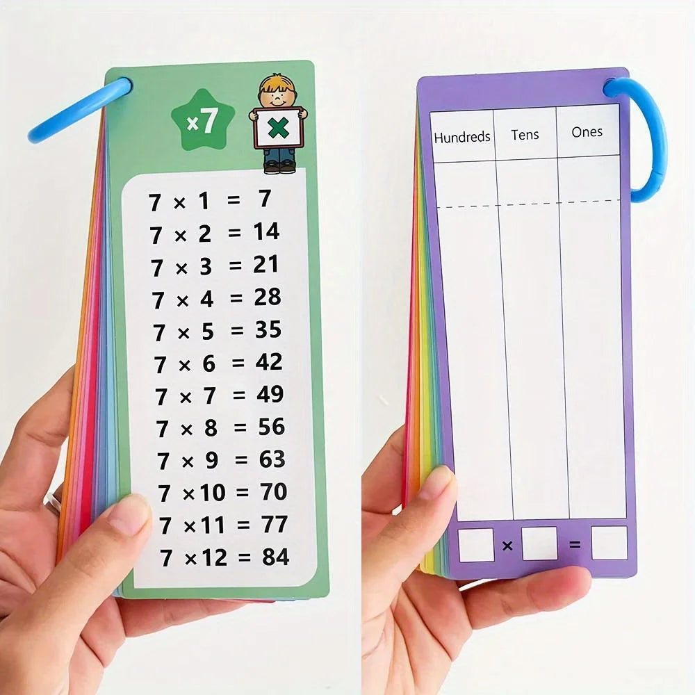 A hand holds a green multiplication flash card showing various 7 times tables, next to a purple flash card with a multiplicat