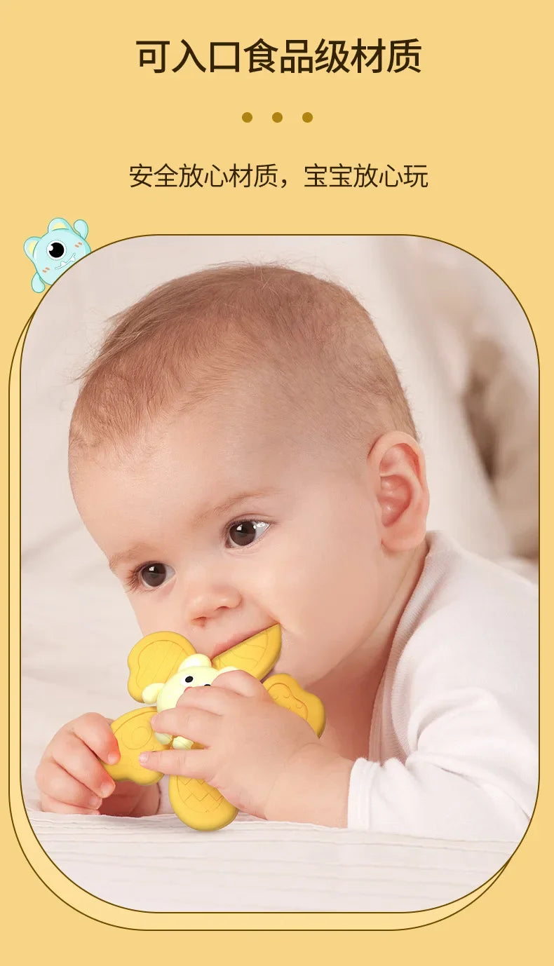 A baby is playing with a yellow suction cup spinner bath toy.