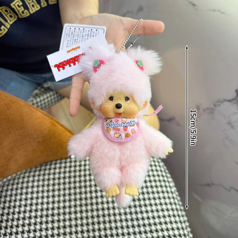 A pink Monchhichi plush toy with a yellow nose and pink ears is being held, showing its size.