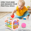 A toddler plays with a pink plastic shape-sorting toy containing colorful balls on a light blue rug.