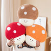 A hand is holding a cute mushroom plush toy with a brown cap and orange body, featuring white polka dots.