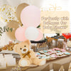 A fluffy yellow teddy bear is displayed on a wooden board surrounded by pink and white balloons for a baby shower.