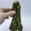 A hand holds a green fabric doll outfit for a fashion set.