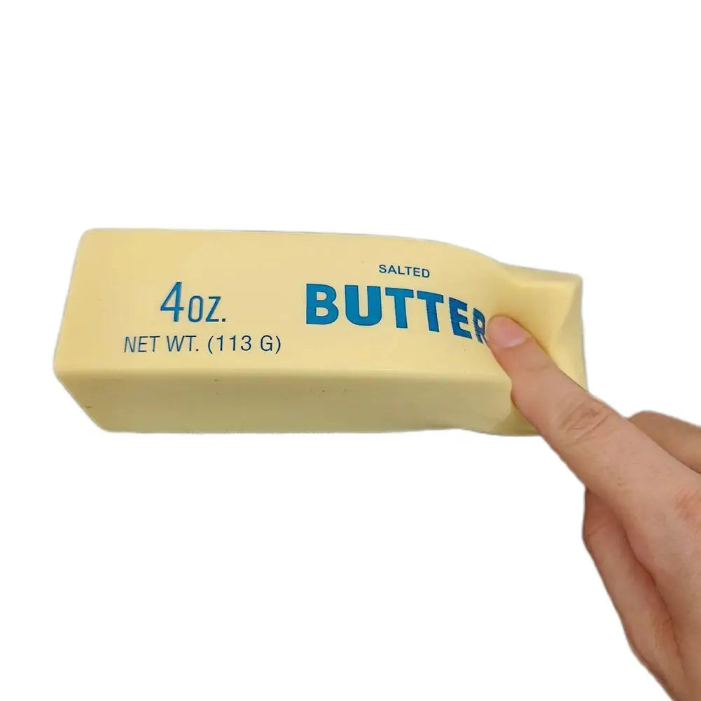 A hand holds a yellow salted butter squishy stress relief toy labeled 4oz net wt 113g