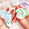 A hand holds various squishy sensory stress balls in pastel colors including pink, purple, and light green.