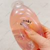 A hand holds a translucent pink fruit bottle stress ball with a squishy fidget toy inside.