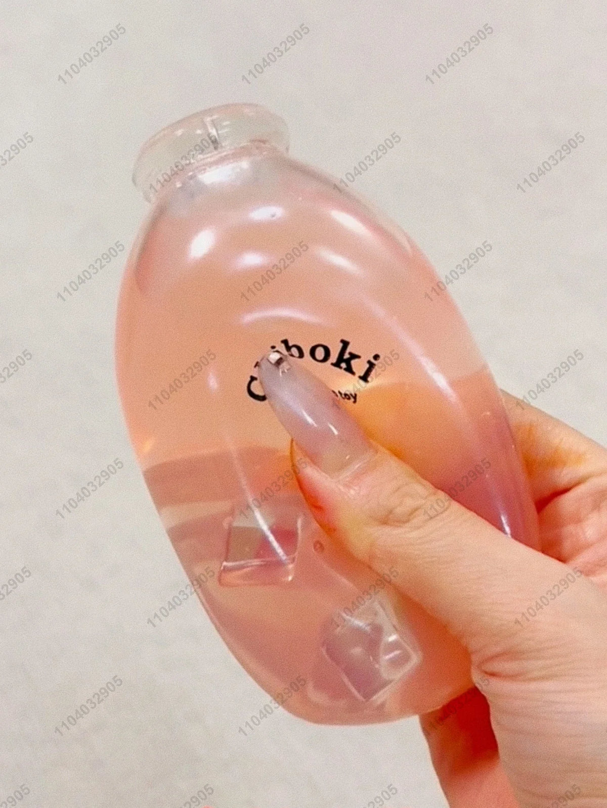 A hand holds a translucent pink fruit bottle stress ball with a squishy fidget toy inside.