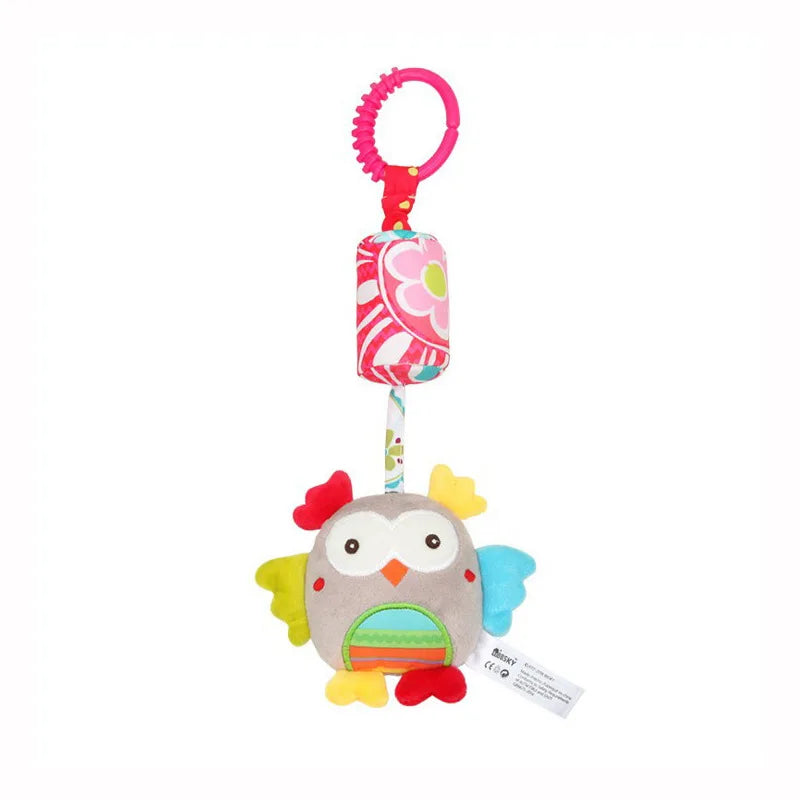 A plush owl hanging rattle toy with a pink and white striped ribbon and a pink ring.