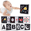 A baby is shown next to a black and white sensory cloth book featuring stars, rainbows, and letters A through C.