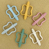 A collection of silicone teethers in various colors and shapes, including a yellow, light blue, pink, and white ones.