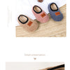 Three pairs of cozy plush baby slippers in beige, pink, and gray with anti-slip soles displayed on a wooden surface.