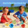 Two young children play in the sand with colorful stacking cups and floating bath toys.