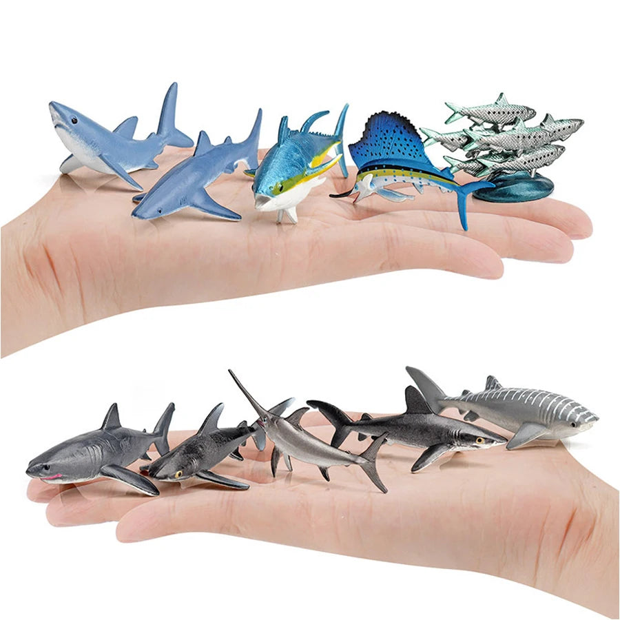 A hand holds a set of realistic mini ocean animal figurines including whales, sharks, dolphins, turtles, and penguins.