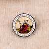 An enamel pin featuring a depiction of a bear with a beard and text surrounding it.