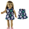 A doll wearing a navy blue dress with a green and white floral pattern.